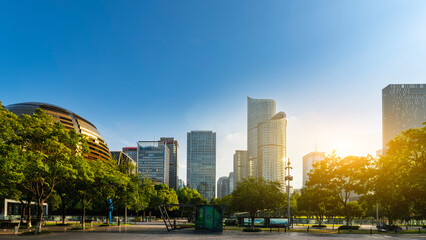 Urban skyline with modern buildings and green trees under clear blue sky