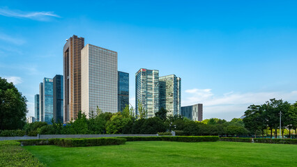 Modern urban buildings with green lawn in front under clear blue sky