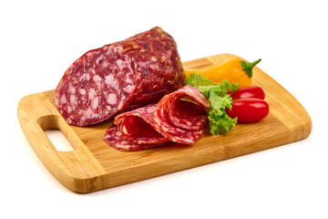 Salami slices and sausage with yellow and red peppers, and lettuce on a wooden board, isolated on...