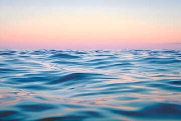 ocean surface at dusk soft golden-pink and deep blue tones in the sky