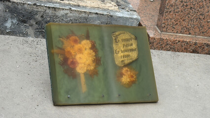 A memorial plaque on a tomb with the French quote "Le temps passe, Le souvenir reste" (Time passes, memory remains)