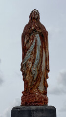 A rusty, old statue of the Virgin Mary