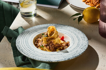 Pappardelle pasta with braised beef cheek, bright natural light, overhead composition