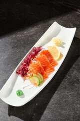 Salmon sashimi in bright lighting, overhead composition on a rectangular white plate