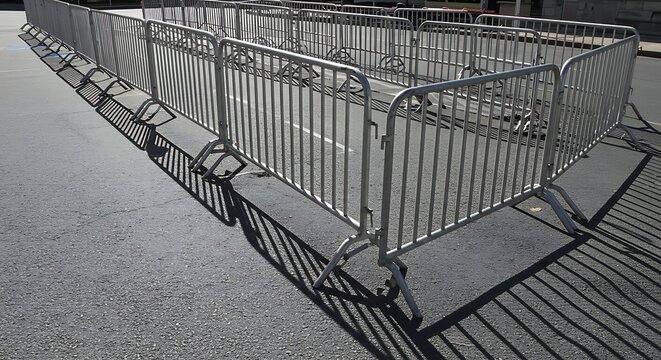 Empty maze of interlocking steel security fences for crowd management at an outdoor event on a sunny day