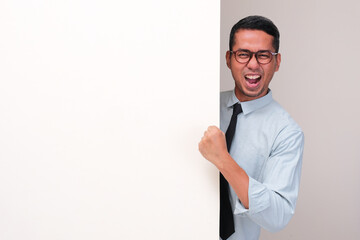 Company employee peeking behind wall clenched fist showing excited expression