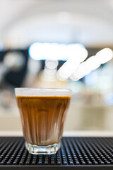 A glass of espresso shot over cold fresh milk create gradient layer called dirty coffee on counter