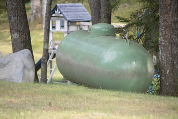 A green residential propane storage tank in a yard