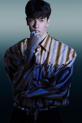 Stylish young man in a striped shirt with a modern pose and a cool atmosphere.