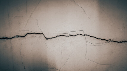Close-up of cracked concrete wall showing deep fracture lines and rough damaged surface texture