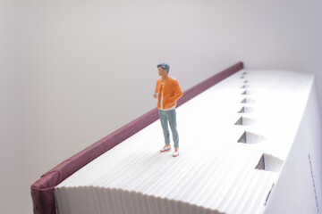 Miniature Figure Standing on a Large Book Pages Edge