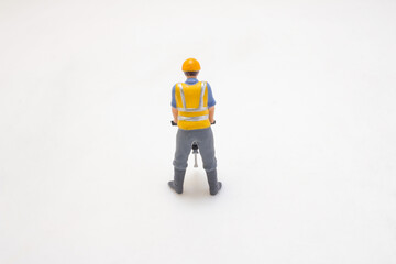 Miniature Worker Using Construction Jackhammer On Clean Background