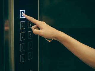 Cropped hand pressing button 5 on elevator panel, closeup
