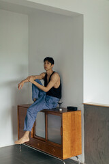 Stylish young man sitting on mid-century furniture in a modern indoor setting.