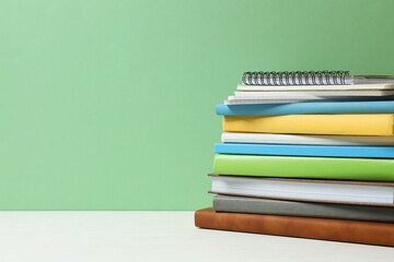 A large stack of books and notebooks on the table

