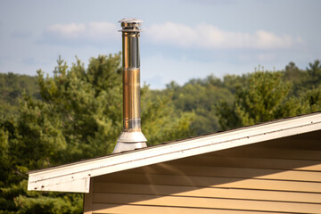 A metal chimney on the roof of a house on a sunny day