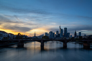 Fototapeta premium Frankfurt skyline reflecting in main river at sunset with bridge