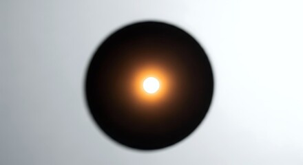 A vibrant light sphere glows warmly in the center of a dark, abstract circular shape, contrasted against a clean, light grey background. Perfect for minimalist and modern aesthetics.