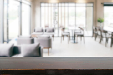 Wooden table surface in sharp focus with a blurred interior of a bright, modern cafe or restaurant...