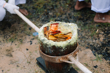 A close-up shot of a crucible containing what appears to be molten metal, held by a long handle, suggesting a process of casting or smelting.