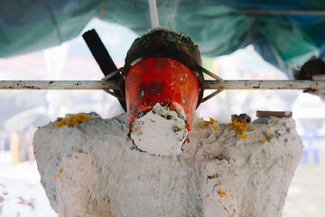 A close-up shot of a crucible containing what appears to be molten metal, held by a long handle, suggesting a process of casting or smelting.