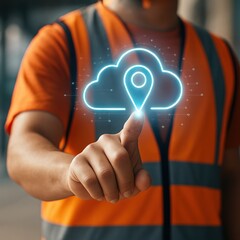 A person in an orange safety vest touches a glowing cloud-based location icon, highlighting digital technology integration in a work environment.
