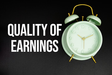 Quality Of  Earnings text with alarm clock on black background