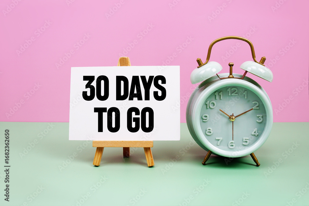 Poster 30 days to go text with alarm clock on pink and green background