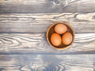 A fresh chicken eggs in a wooden saucer on a wooden table