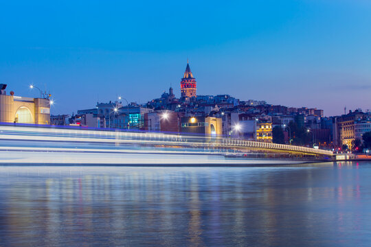 Fototapeta Galata Tower, Galata Bridge, Karakoy district and Golden Horn with motion speed light of passing ferry in the foreground at night istanbul - Turkey  