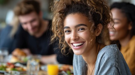 Obraz premium Joyful Dining: A cheerful young woman radiating happiness at a social gathering with friends, fostering warmth and camaraderie in a comfortable setting.