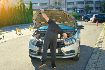 Man checking engine under open hood of silver car, vehicle repair, troubleshooting, and automobile...