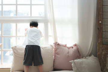 The boy looks outside the window, watching the world go by.