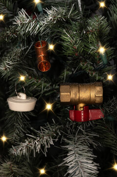 Plumbing Christmas scene with ornaments and plumber tools on pine tree branch close-up.