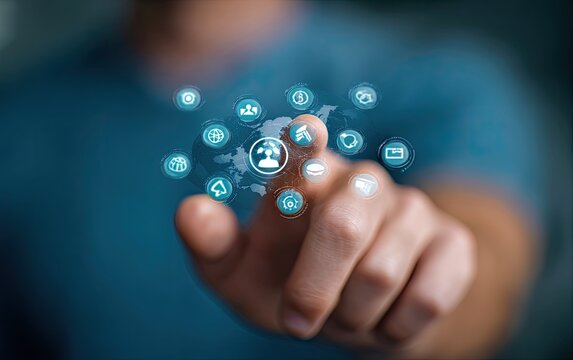 A person's finger touches a holographic interface with various digital icons, including a phone, person, and world map, overlayed on a teal-colored shirt