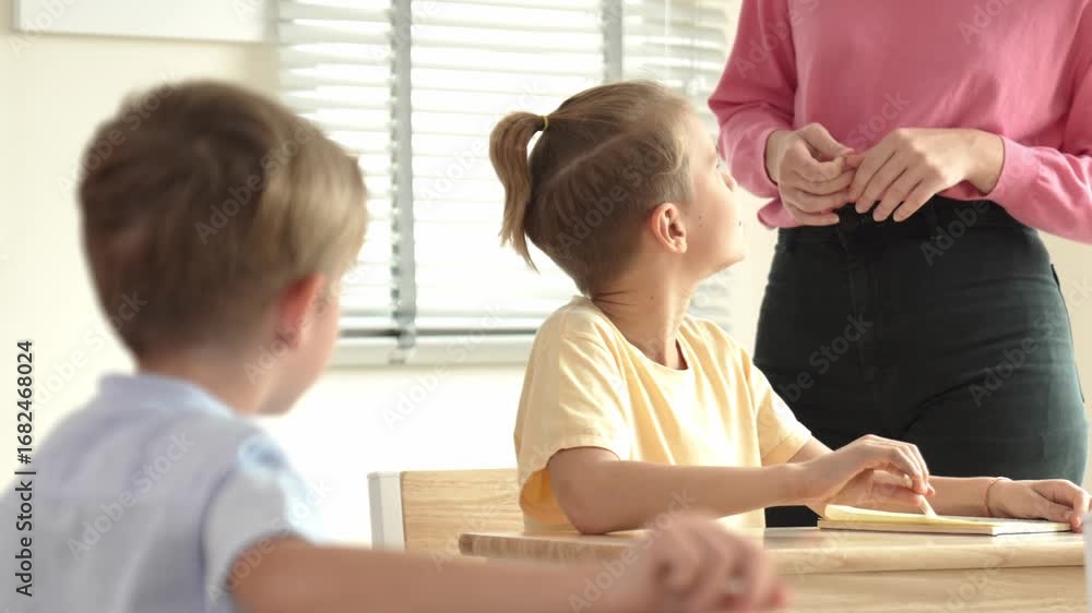 Poster beautiful teacher explaining test while caucasian boy doing classwork and listening explanation. cut