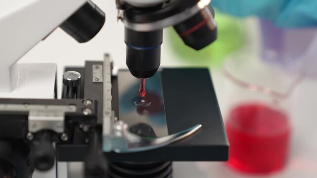 Scientific laboratory researcher drop blood sample on microscopic slide for medical examination or new diagnostic tool. Microbiologist, medical worker conduct experiment in lab. Slow motion. Rigid.