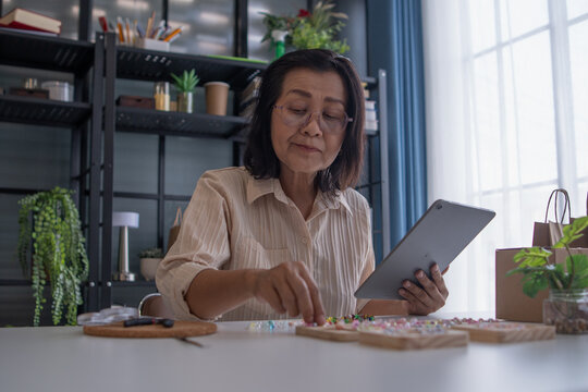 Mature asian woman owner taking online orders with tablet