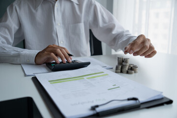 Businessman plans investment, uses his hands to put coins into a piggy bank