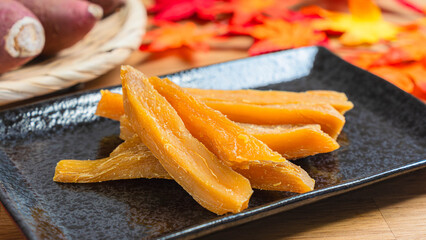 黒皿に盛られた干し芋と秋の紅葉とさつまいも