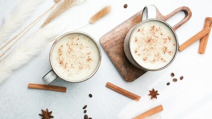 Two cups warm beverage with cinnamon spice, coffee beans, star anise and cinnamon sticks on table. - Powered by Adobe