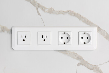 Modern wall outlets. Euro and US standards. Marble background.