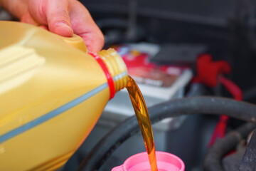 Hand pouring new engine oil for maintenance