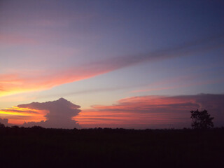 A dramatic sunset paints the sky with hues of orange, pink, and purple over a silhouetted landscape.
