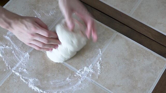 A young man kneads the dough with his hands on the table. Close-up of kneading dough with only hands in the frame