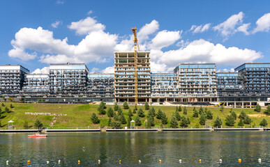 Modern residential complex near water with construction crane. Contemporary building construction.