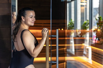 Ritual of calm in sauna light. Woman by the door.