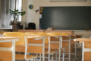 The classroom is set for learning with neatly arranged desks and a chalkboard.