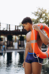 Lifeguard carrying lifebuoy by the poolside: ensuring safety and rescue readiness