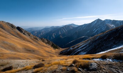vast mountain range under clear blue sky, sunlit peaks with warm golden tones,